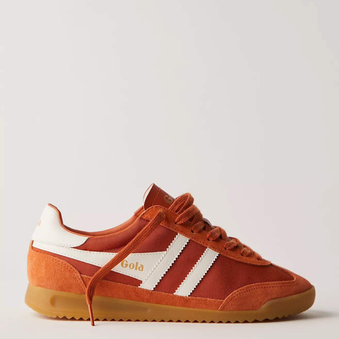 side view of the Gola Tornado Sneaker with rust orange laces and white vintage stripes with a rubber gum sole