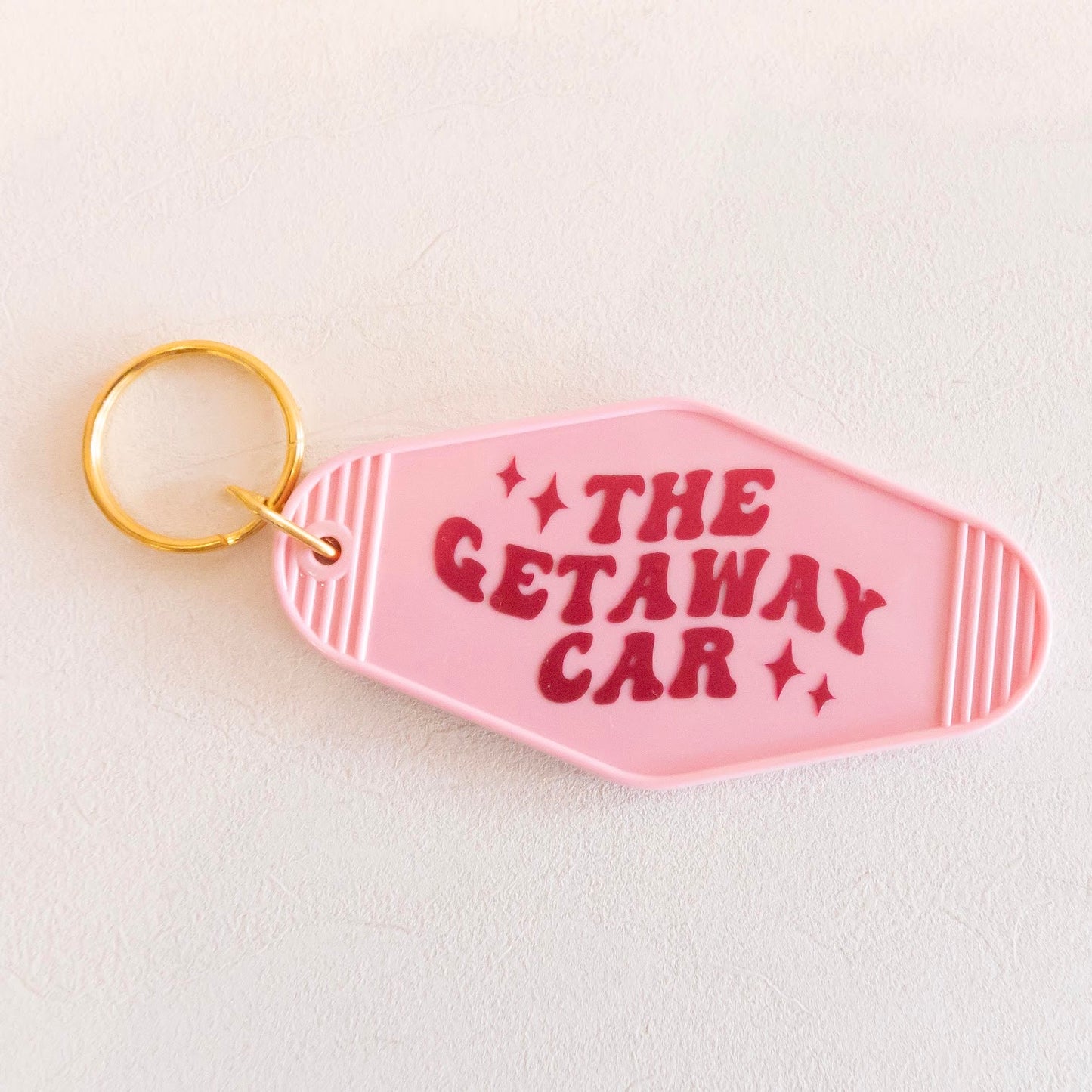 Vintage-inspired keychain with 'The Getaway Car' text and stars, made from white acrylic with a golden keyring. Perfect for adding a quirky, retro touch to your keys.