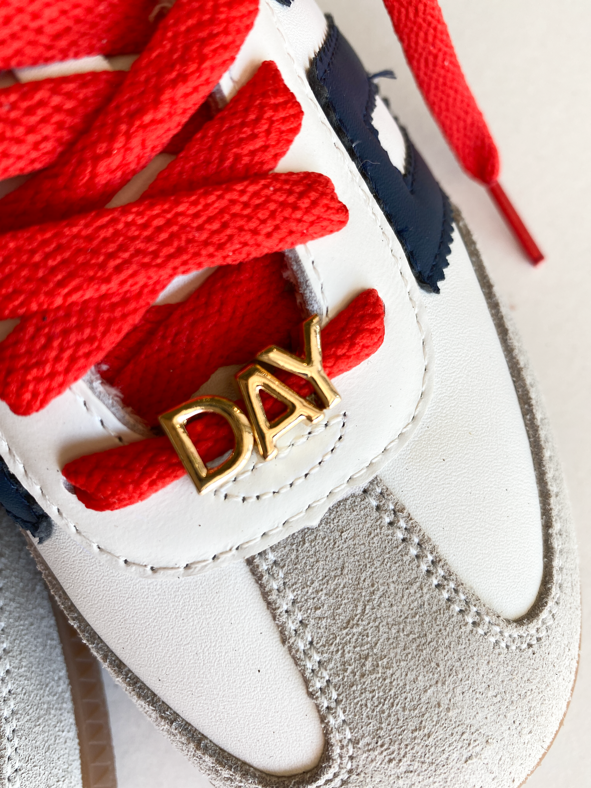 A close-up image of red shoelaces tied in a bow, accompanied by gold letter charms spelling "GAME DAY" displayed below.