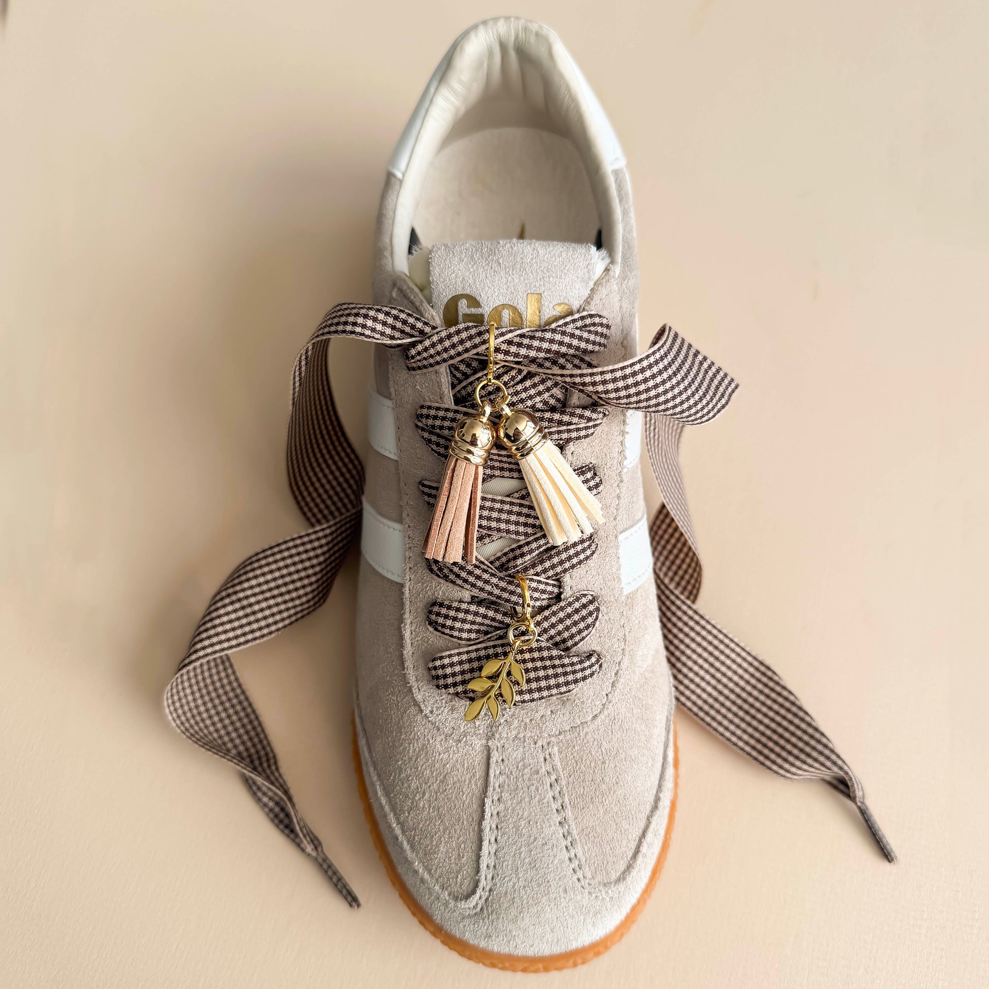 Close-up of brown gingham bow laces with tassel and leaf charms