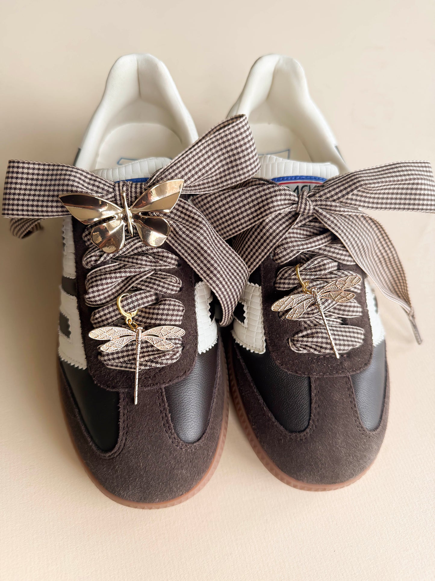 houndstooth laces with a gold butterfly and 2 golden dragonfly charms shoecased on a brown back 70 sneaker