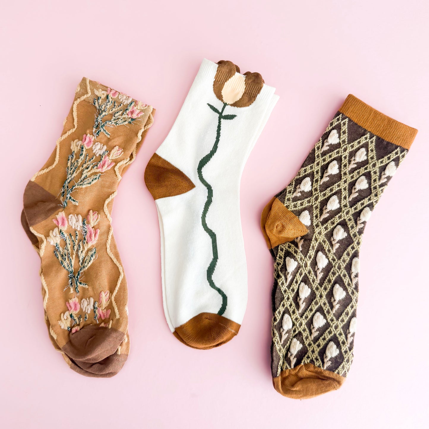Three pairs of patterned socks on a pink background