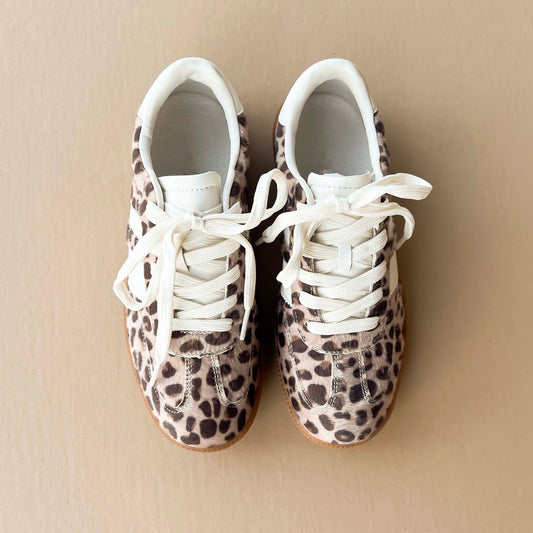 top-down view of leopard-print sneakers with white laces on a neutral beige background. Perfect for casual fashion and versatile styling.