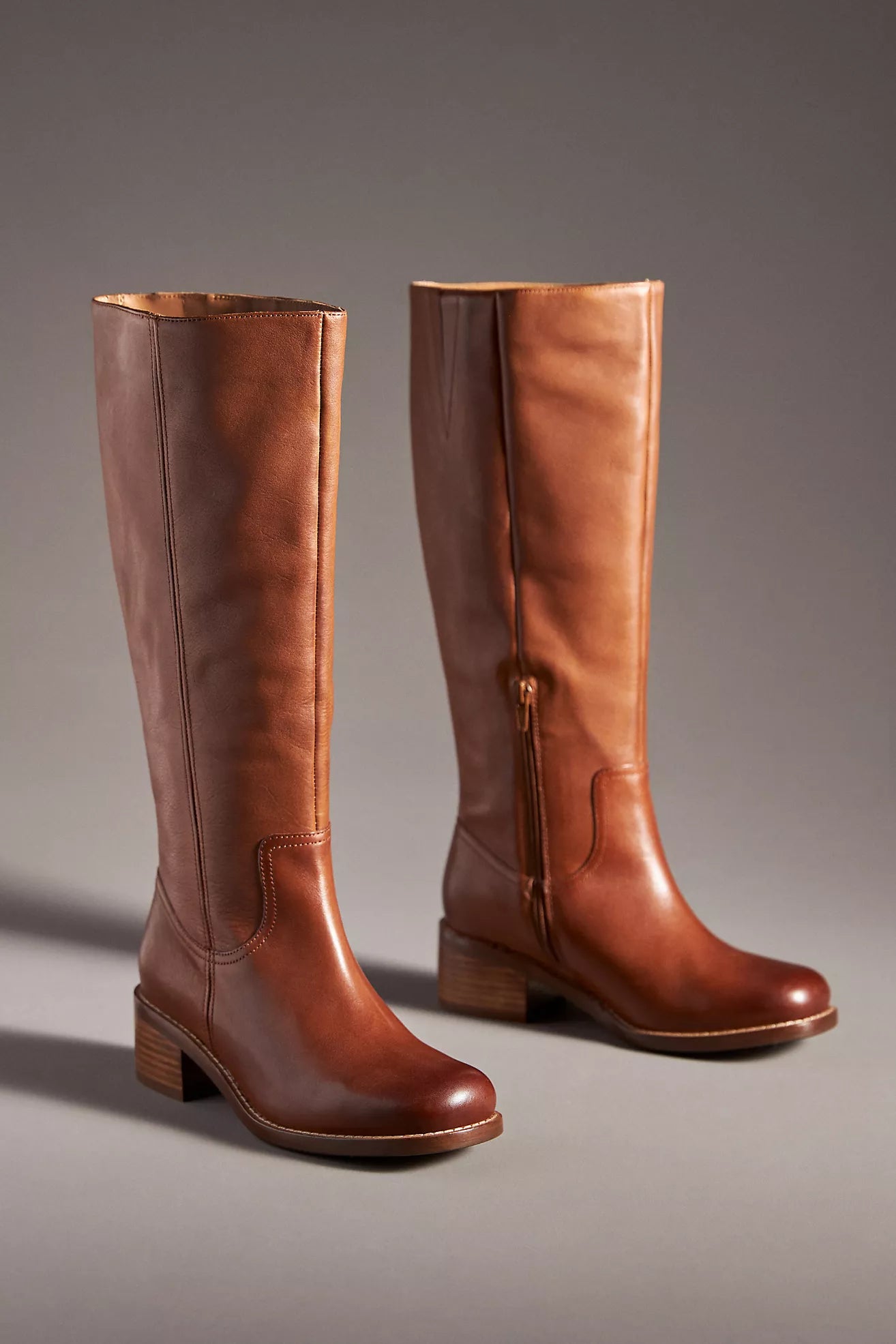 Pair of brown leather knee-high boots on a gray background