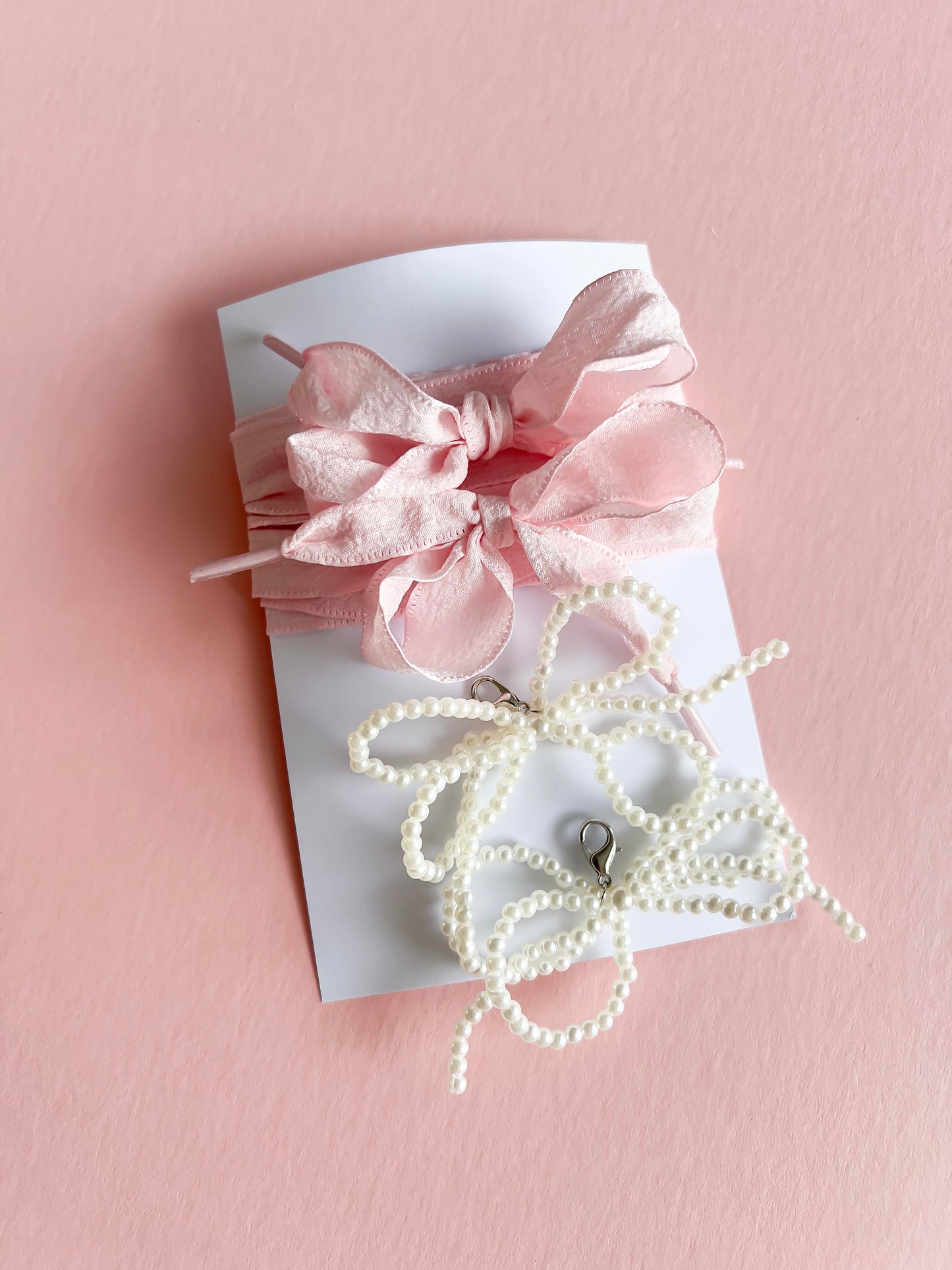 Pink ribbon lace and pearl bow shoe charms set, with a soft fabric ribbon and two pearl bow clips, displayed on a pink background