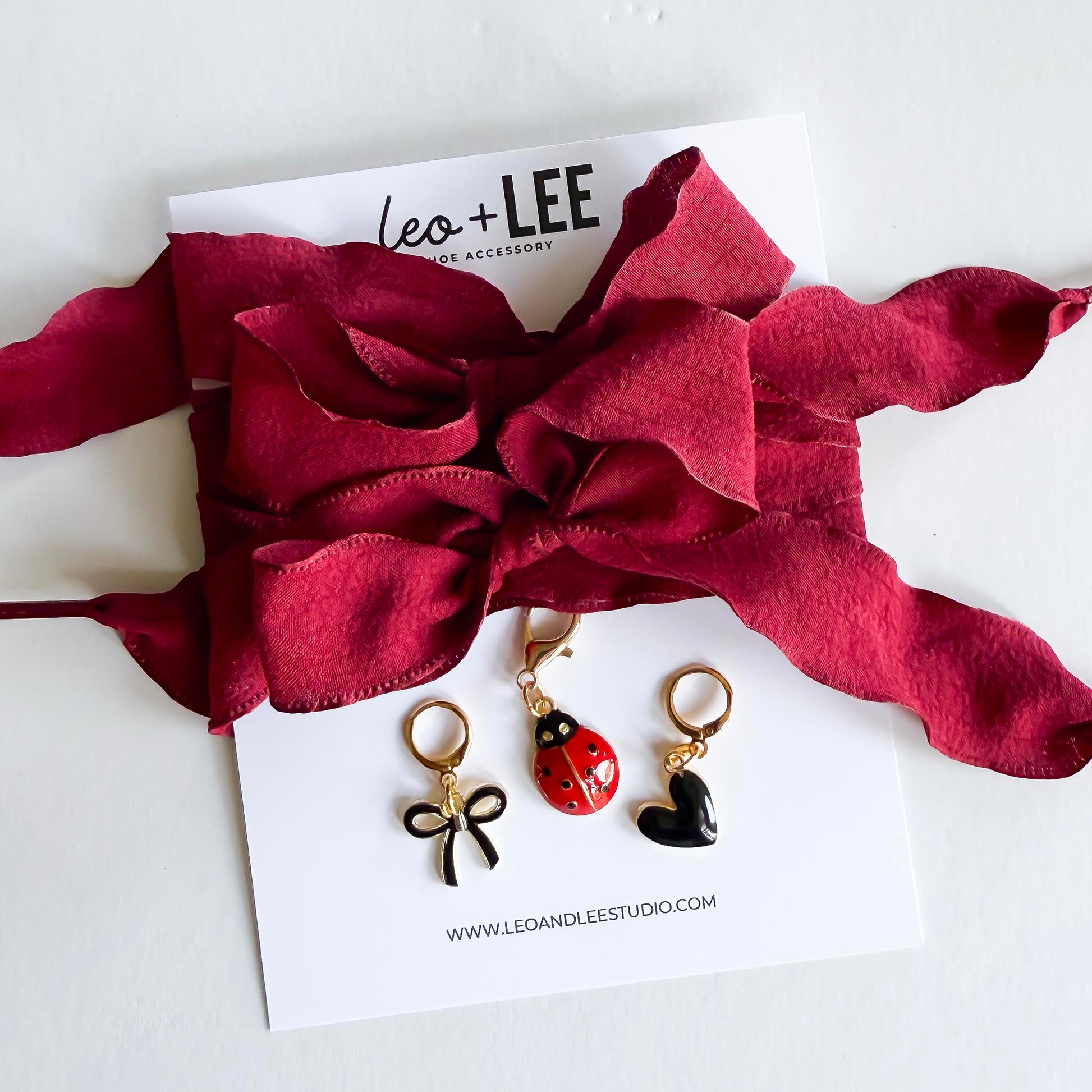 Close-up of Leo + Lee ladybug sneaker charm set on white background