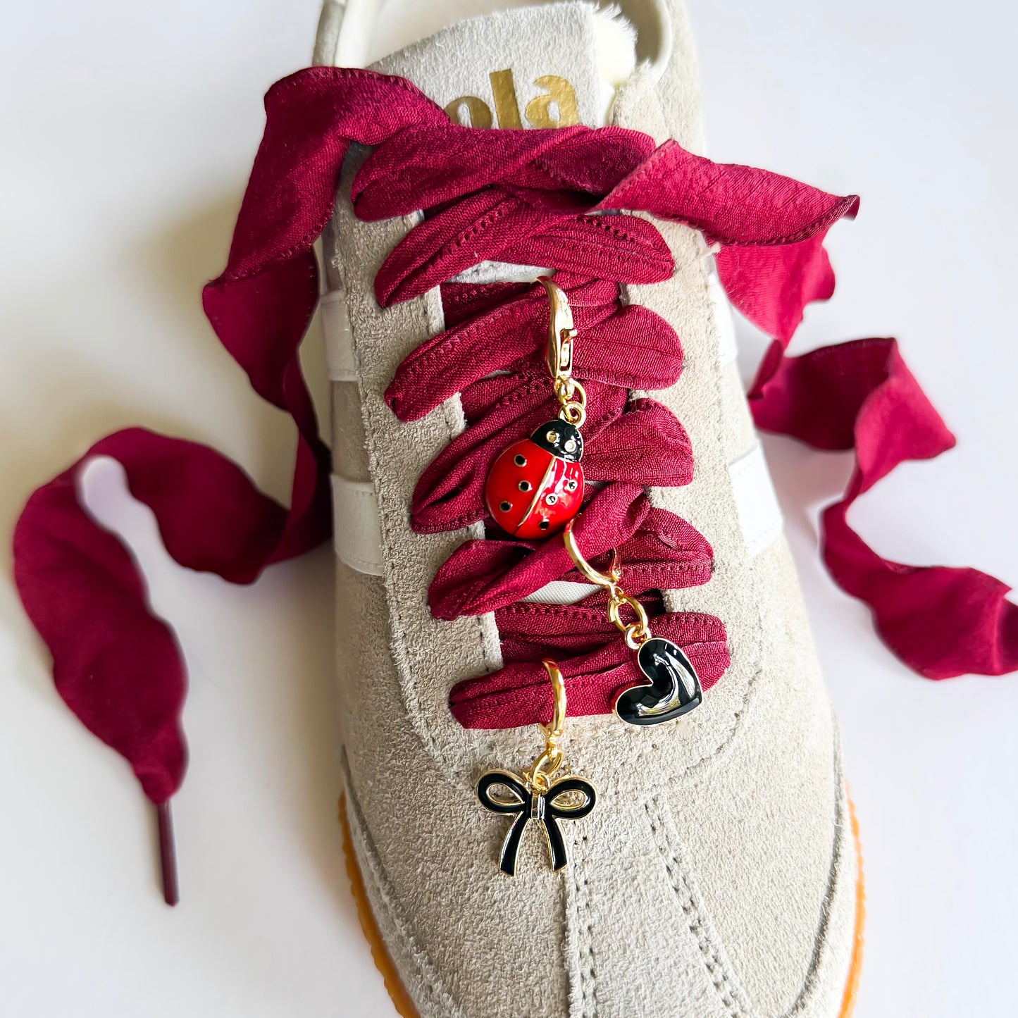 Close-up of Leo + Lee ladybug sneaker charm set on a beige sneaker