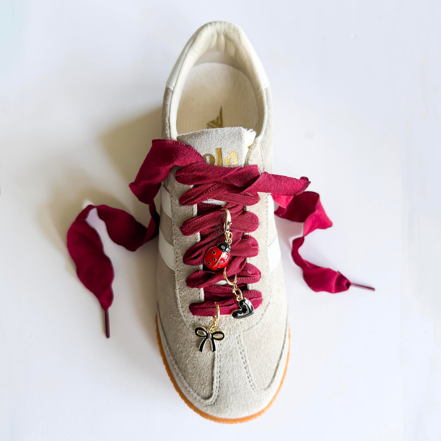 Close-up of Leo + Lee ladybug sneaker charm set on a beige sneaker
