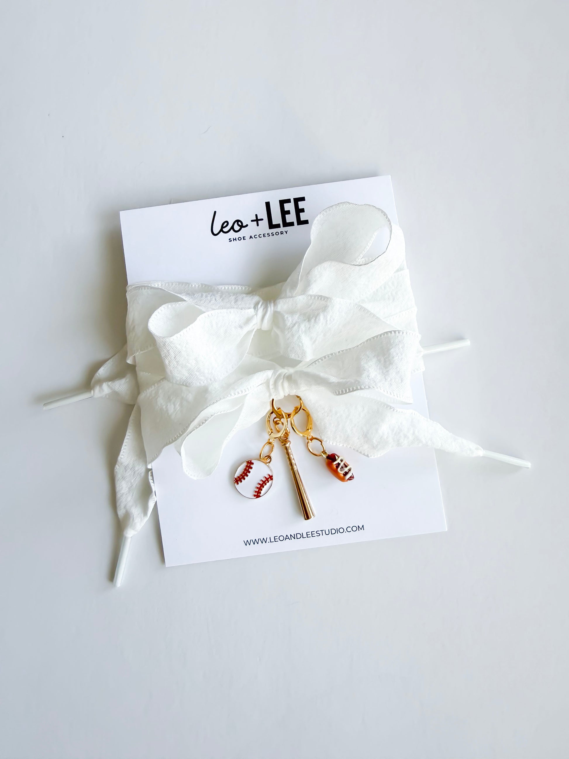 White ruffle laces with sports-themed charms on a white card with 'Leo + Lee' branding.