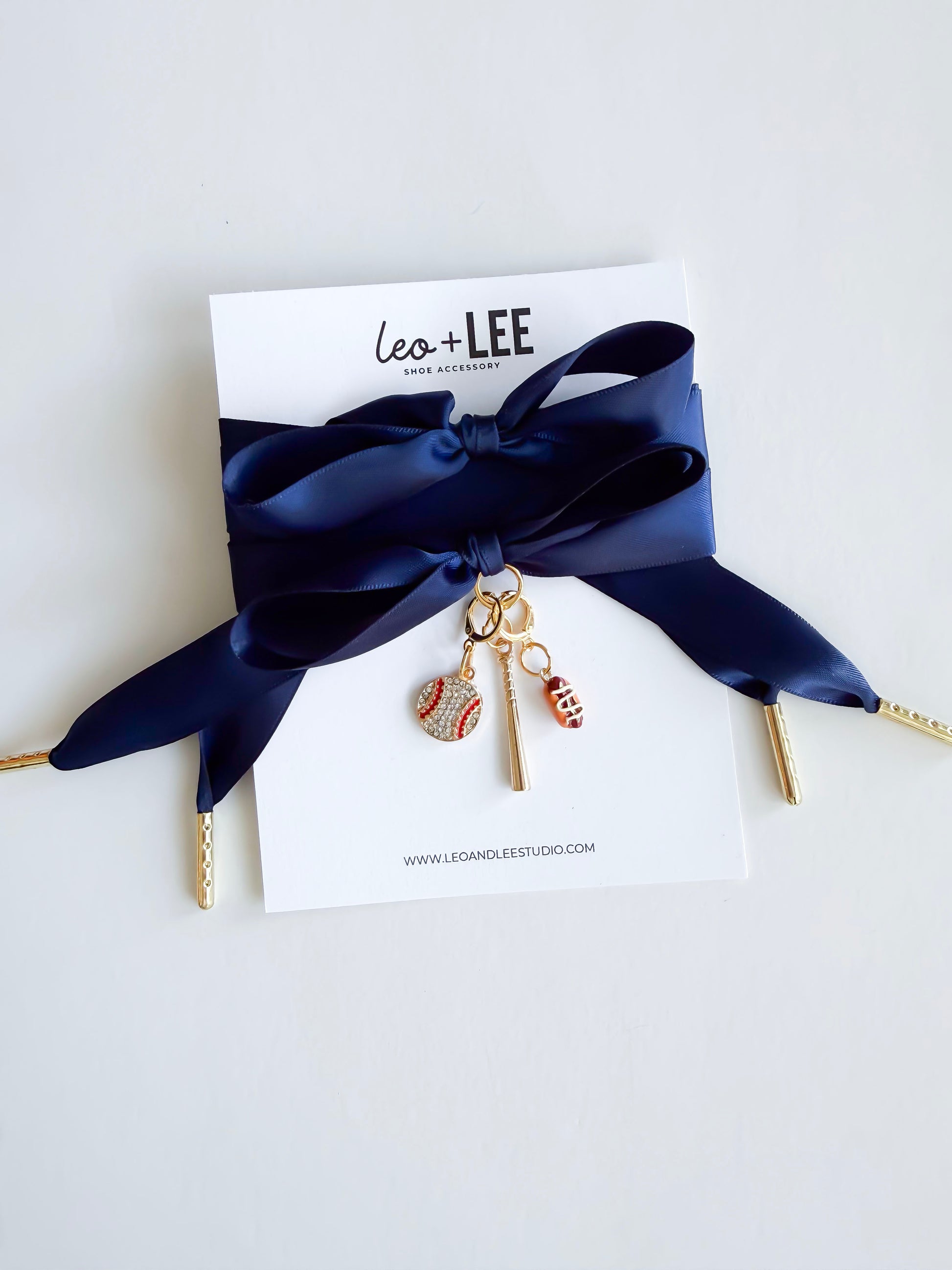 Navy Satin Laces with gold aglets with sports-themed  baseball charms on a white card with 'Leo + Lee' branding.