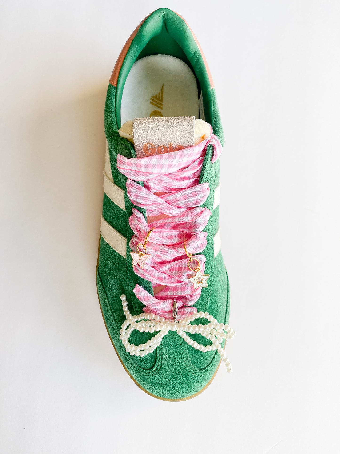 Gold shoe charms with pink butterfly and white star designs, displayed with pink gingham ribbon shoelaces and pearl bead shoelaces on white background.
