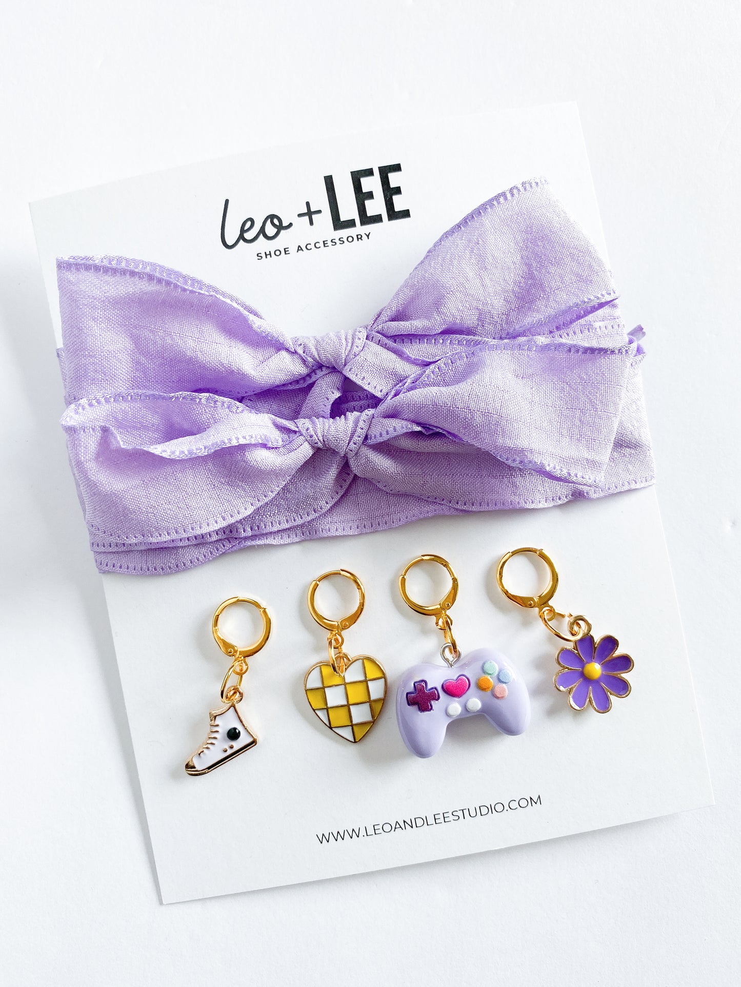 Assorted kids sneaker charm sets displayed in rows, each featuring 100cm bow-style ribbon shoelaces and four colorful enamel shoe charms on branded cards.