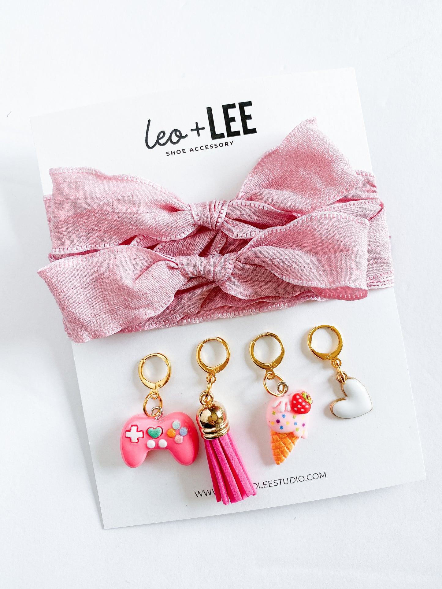 Assorted kids sneaker charm sets displayed in rows, each featuring 100cm bow-style ribbon shoelaces and four colorful enamel shoe charms on branded cards.
