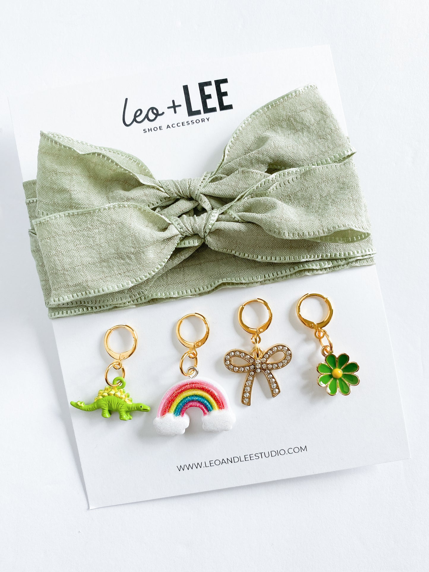Assorted kids sneaker charm sets displayed in rows, each featuring 100cm bow-style ribbon shoelaces and four colorful enamel shoe charms on branded cards.