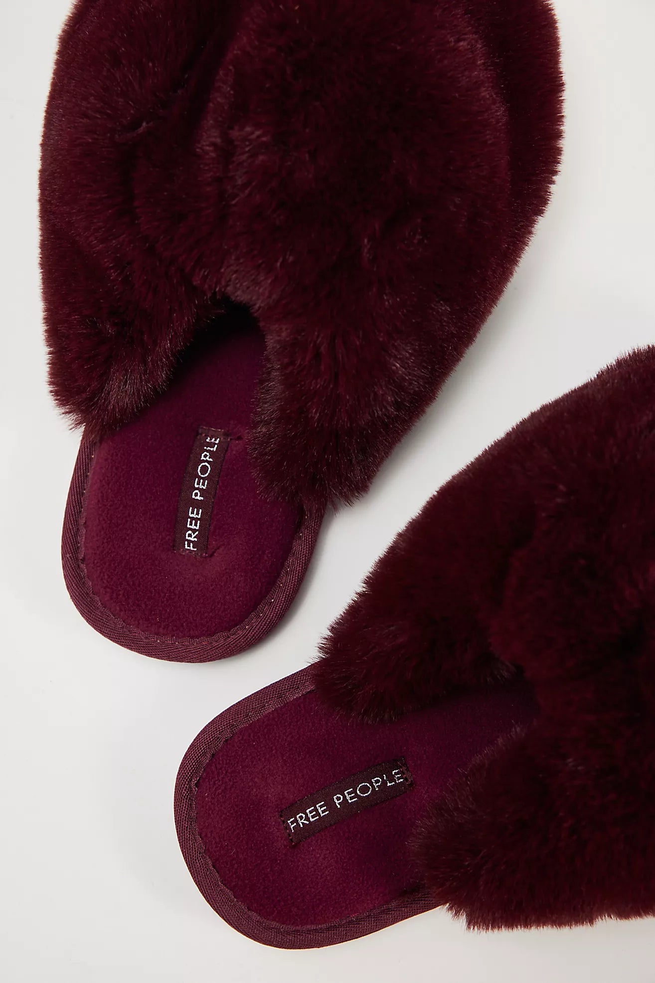 Maroon fuzzy slippers with 'Free People' label on a white background