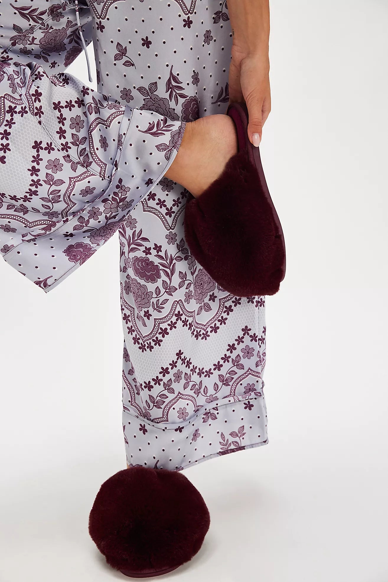 Person wearing a patterned outfit with maroon shoes on a white background