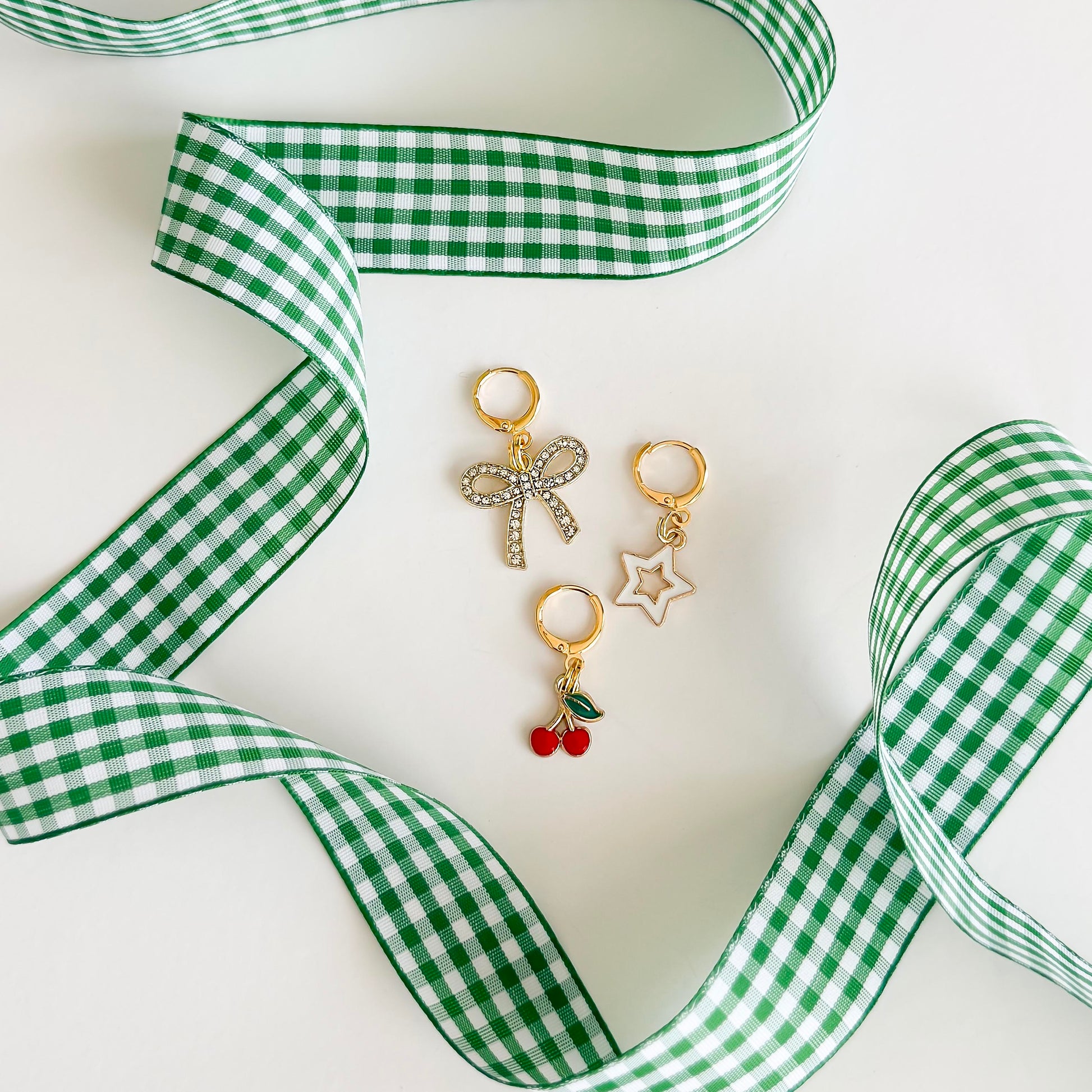 Green gingham bow shoelace accessories with gold sneaker charms – star, cherry, and rhinestone bow – laid out on a Leo and Lee Studio card.