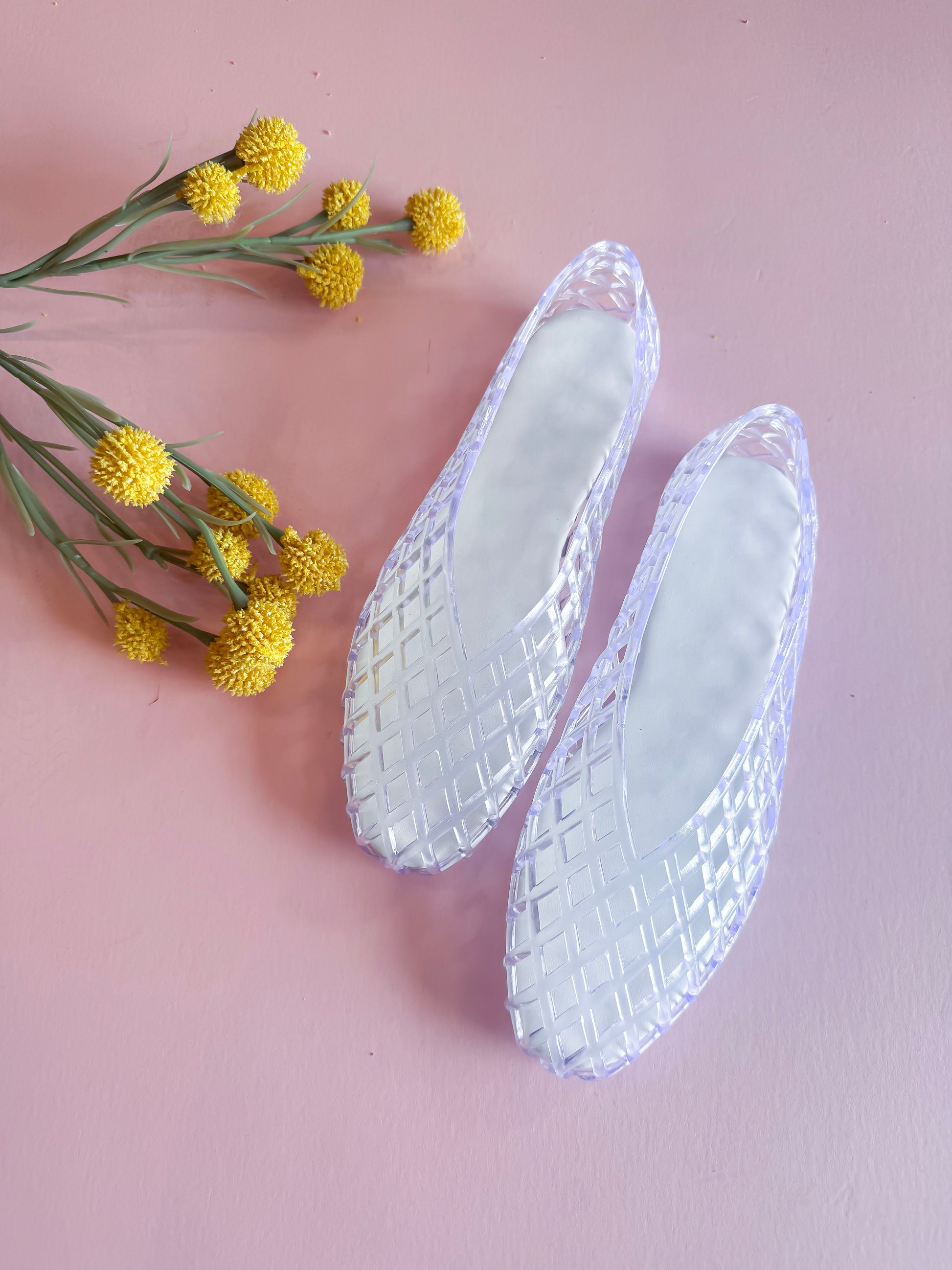 Clear shoe insoles with textured pattern on a pink background with yellow flowers.