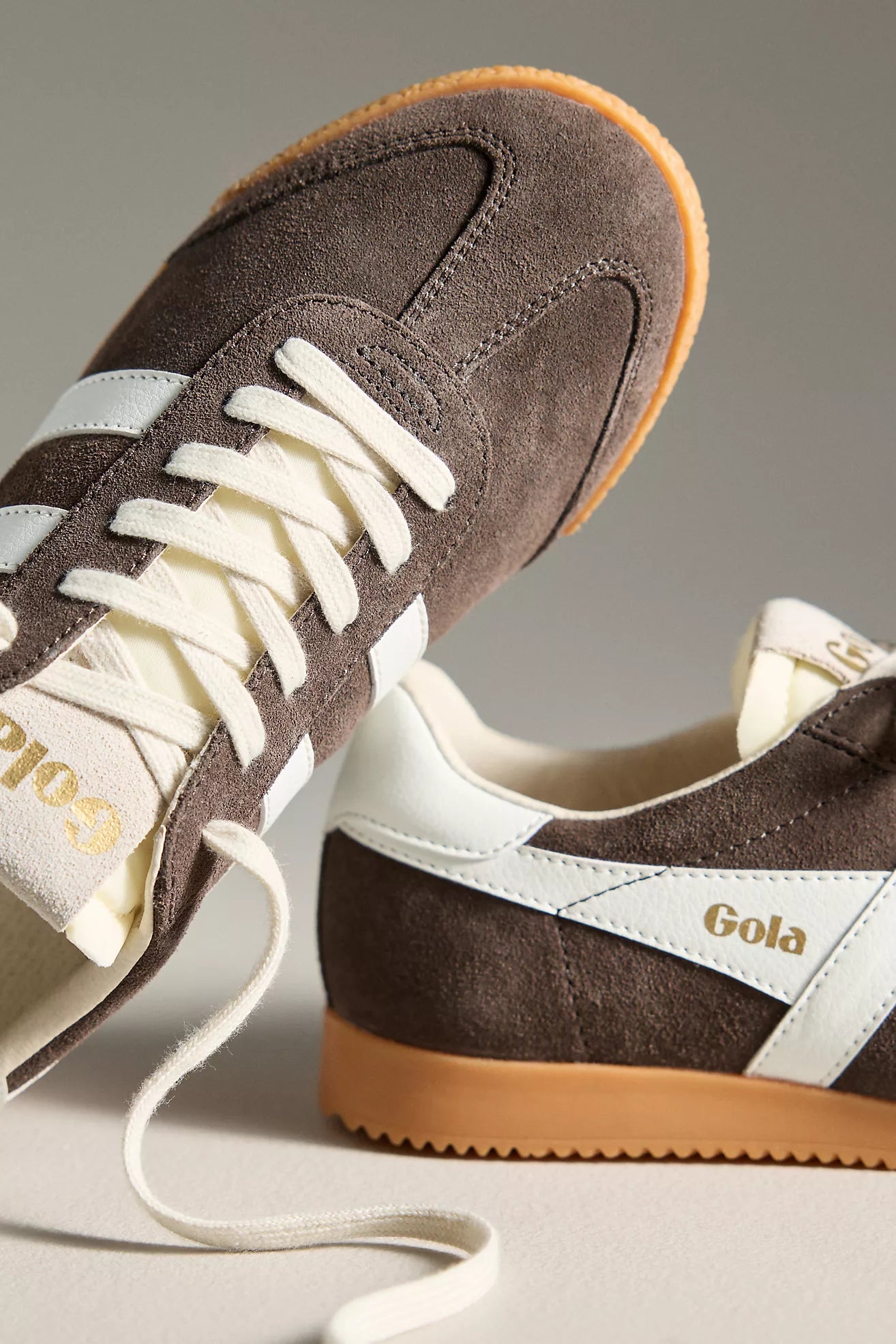 Brown suede Gola shoes with white laces on a neutral background