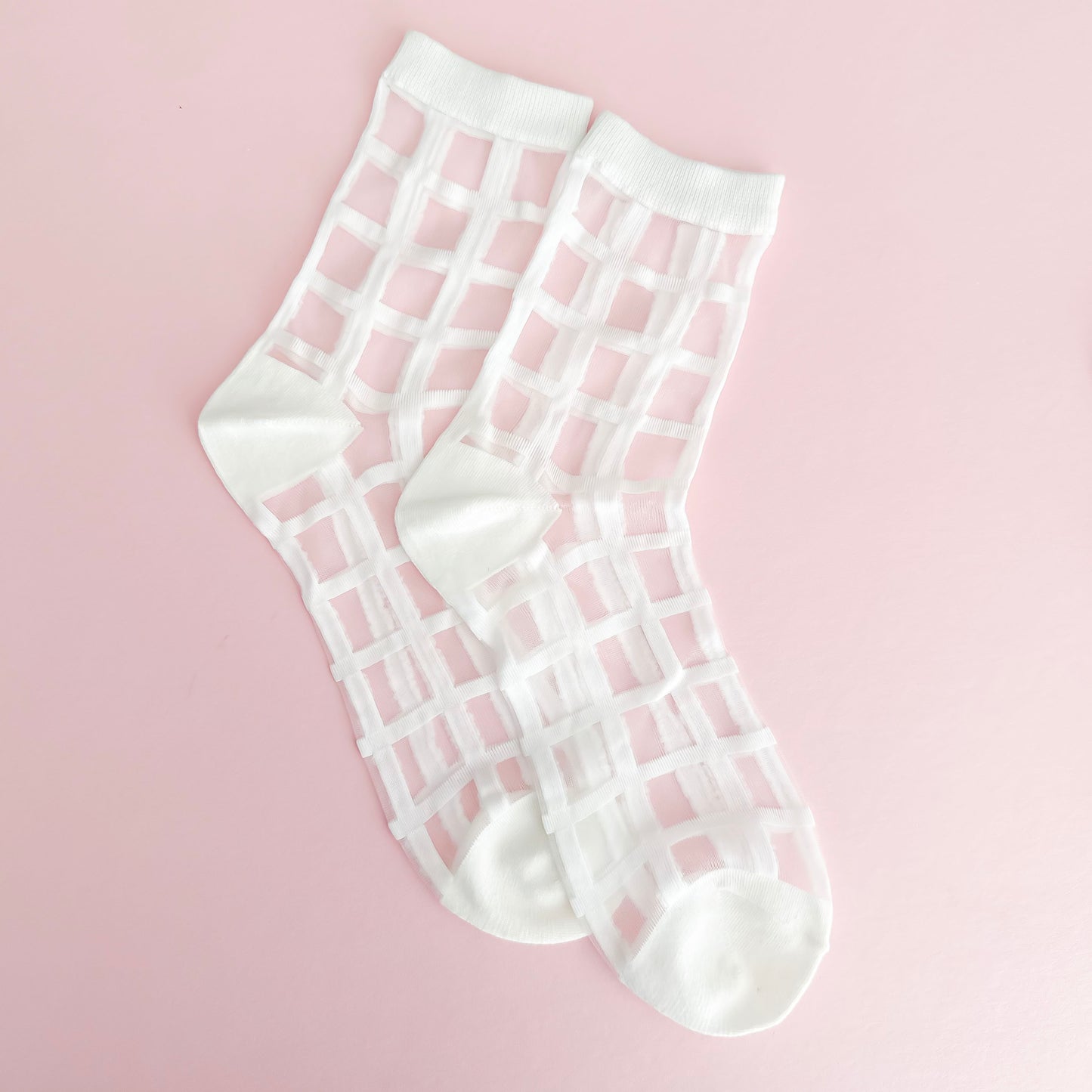 White grid-patterned socks on a pink background