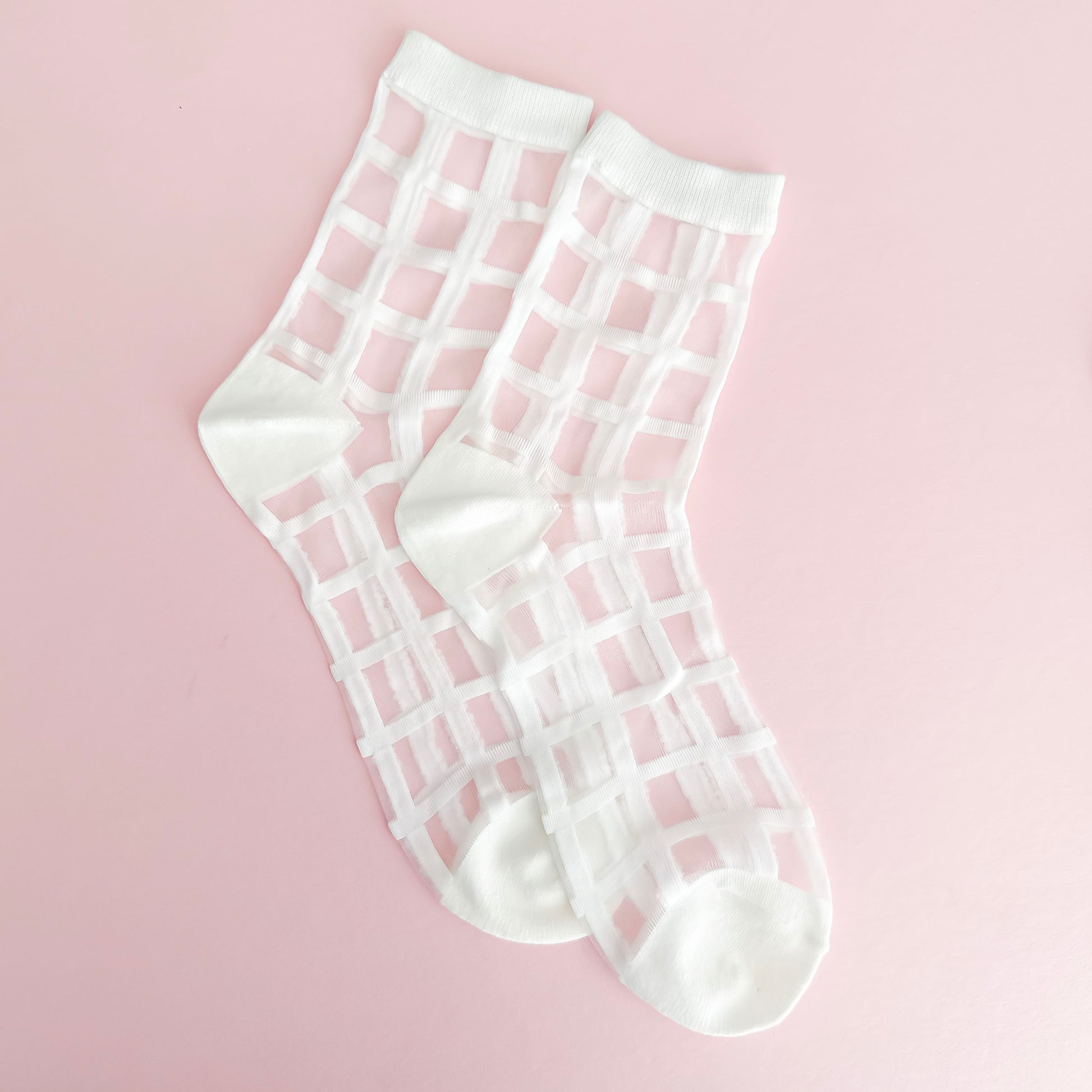 White grid-patterned socks on a pink background