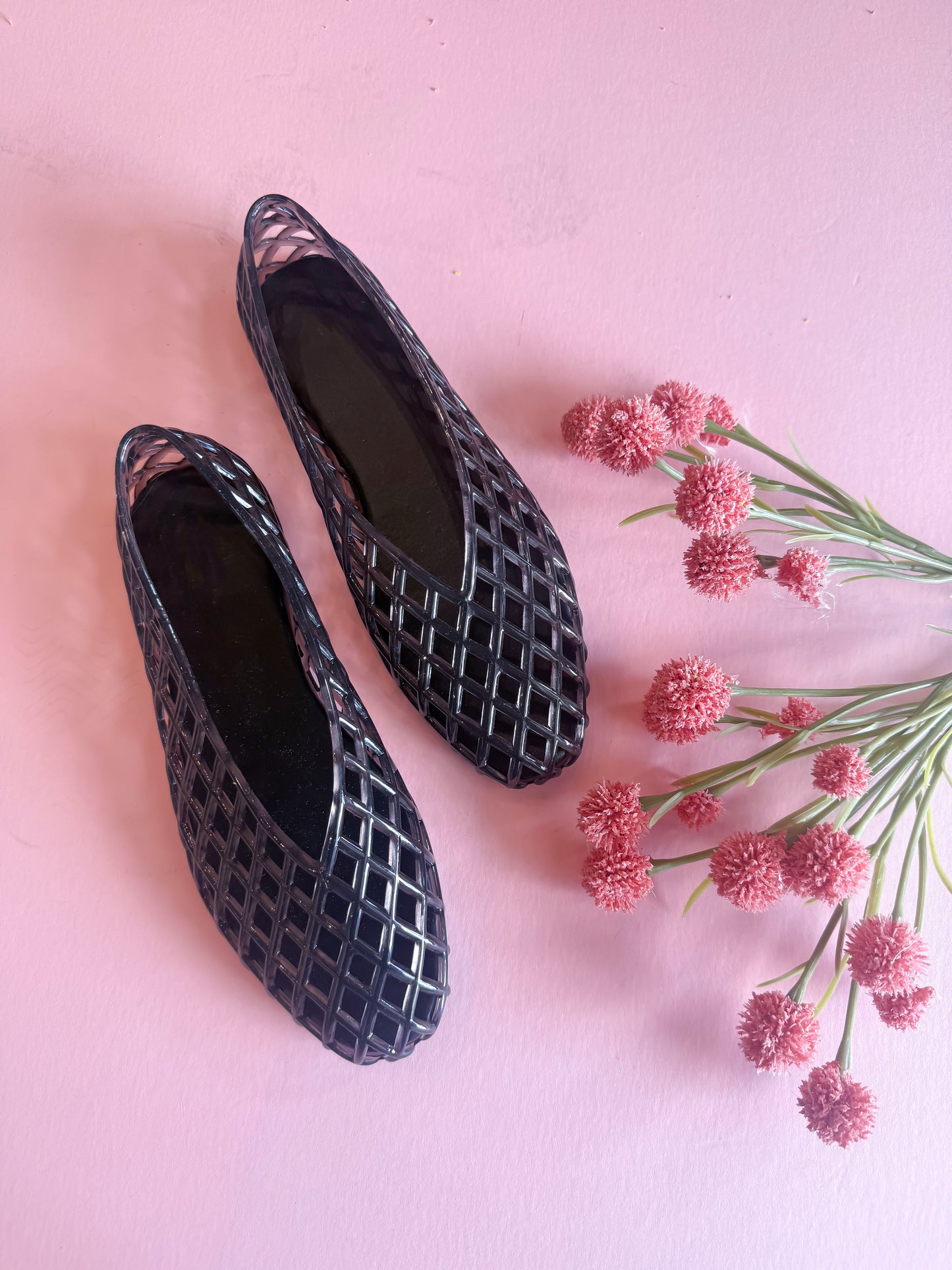 Black textured shoes on a pink background with pink flowers