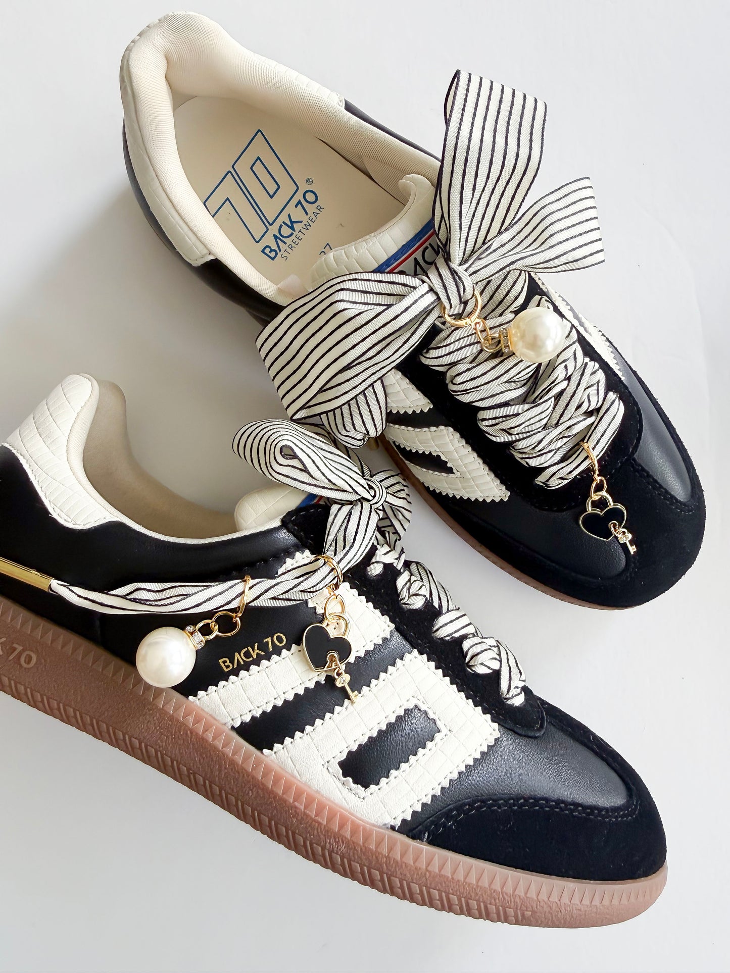 Black and white sneakers with decorative laces and charms on a light background