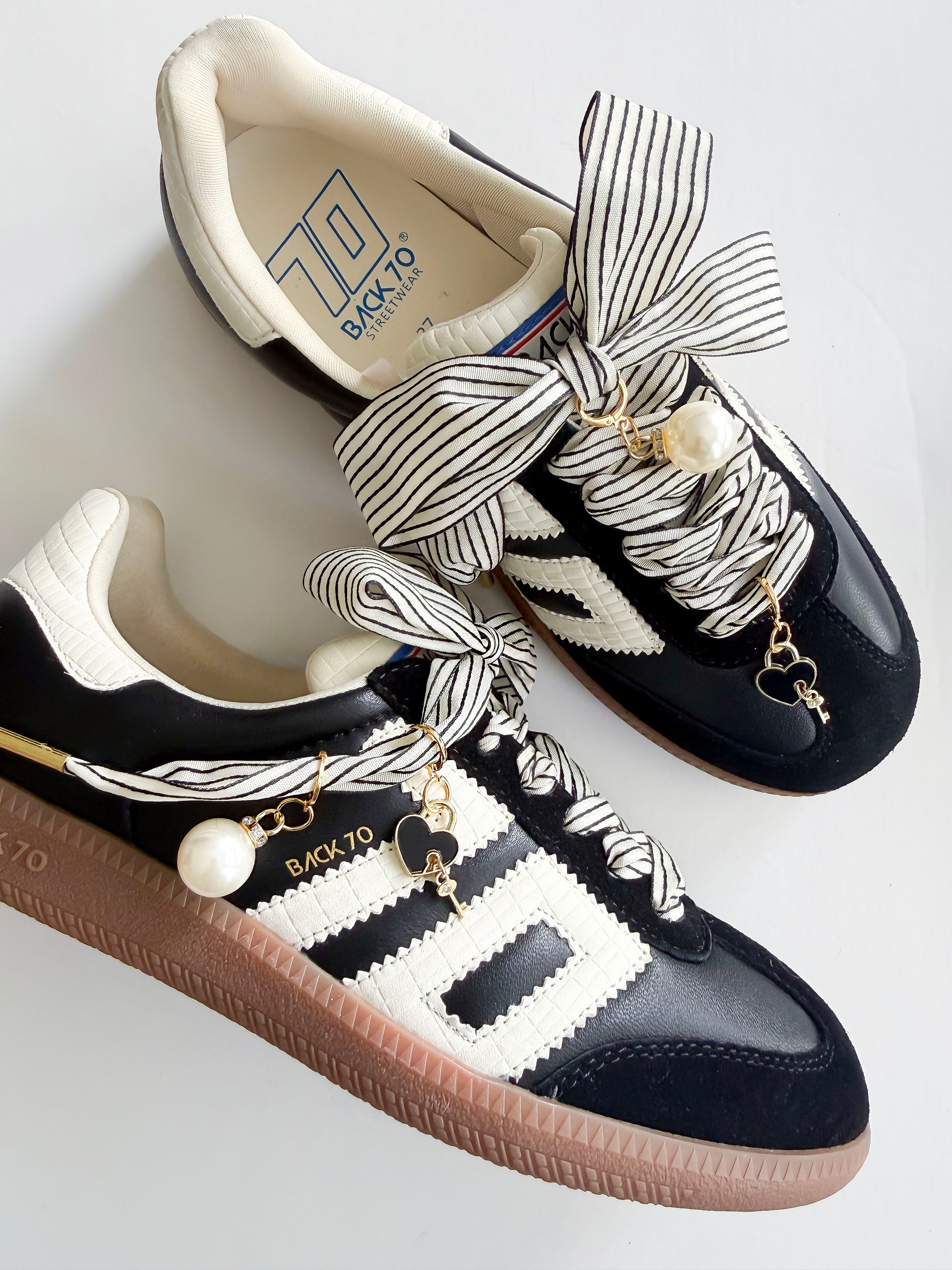Black and white sneakers with decorative laces and charms on a light background