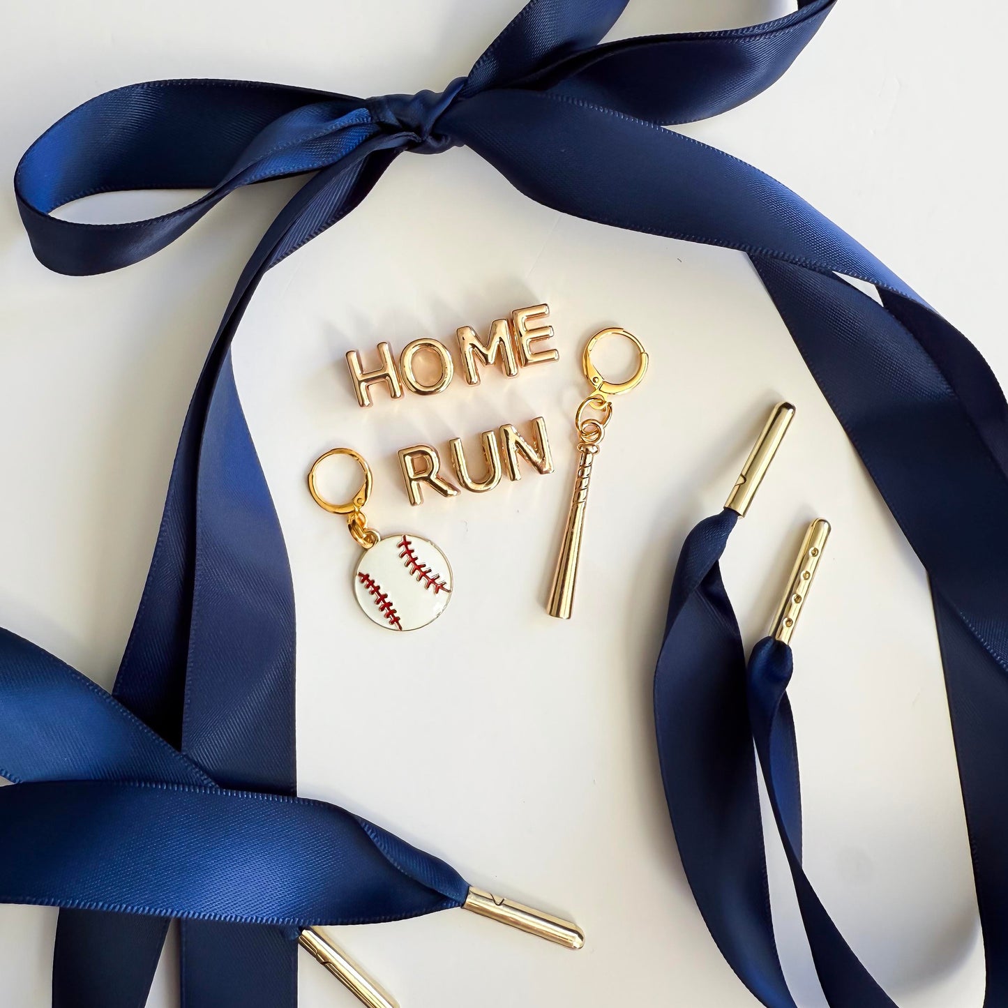Navy satin sneaker laces with gold “HOME RUN” charms, baseball charm, and bat charm