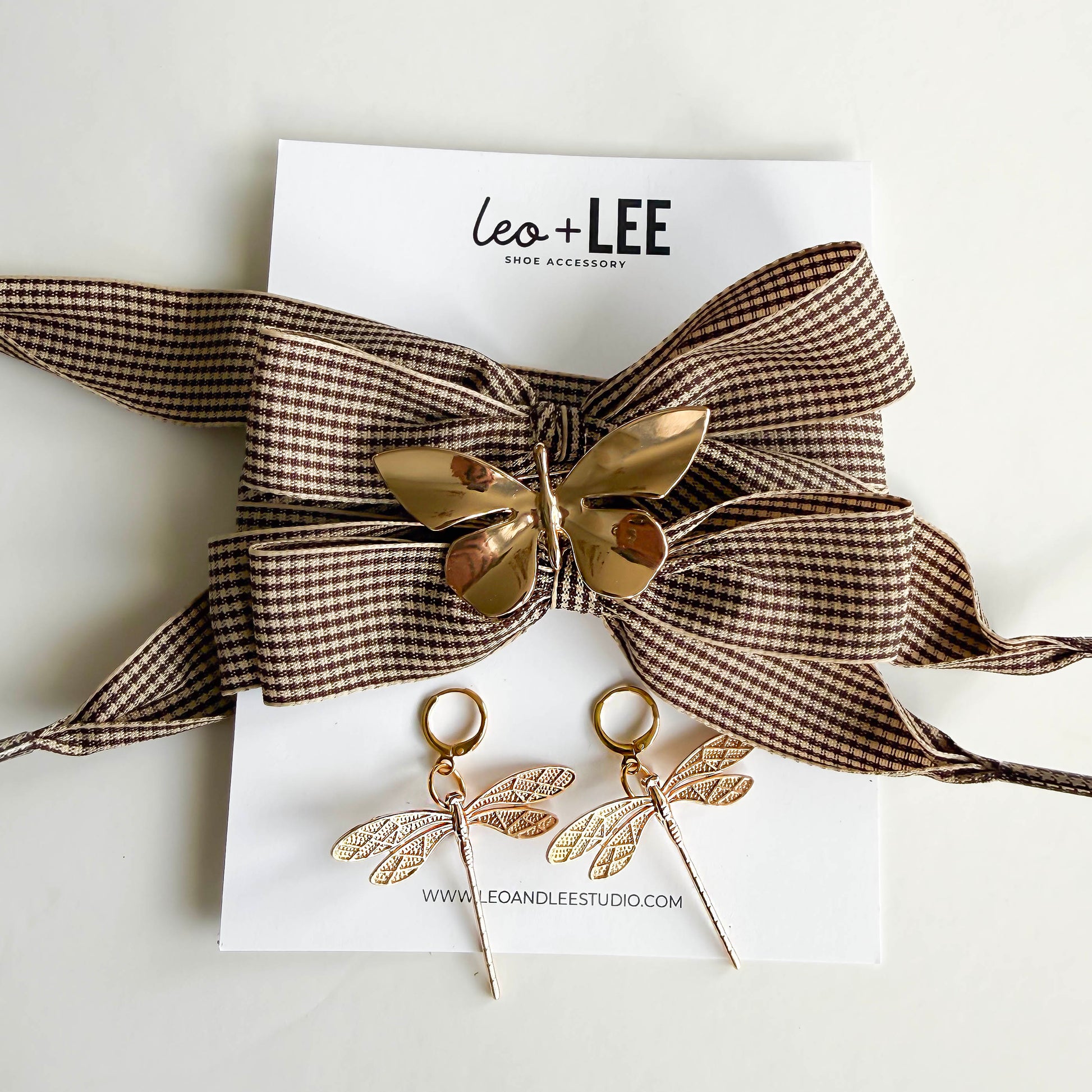 houndstooth laces with a gold butterfly and 2 golden dragonfly charms shoecased on a white leo and lee card