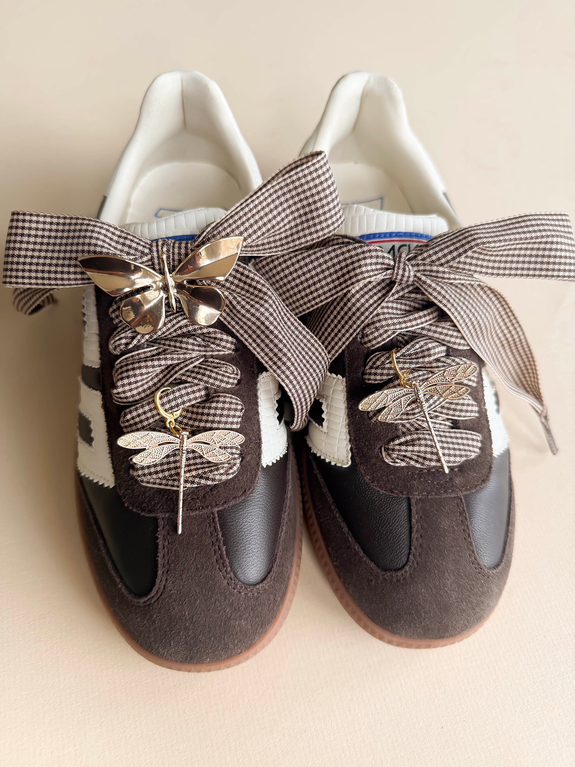 houndstooth laces with a gold butterfly and 2 golden dragonfly charms shoecased on a brown back 70 sneaker