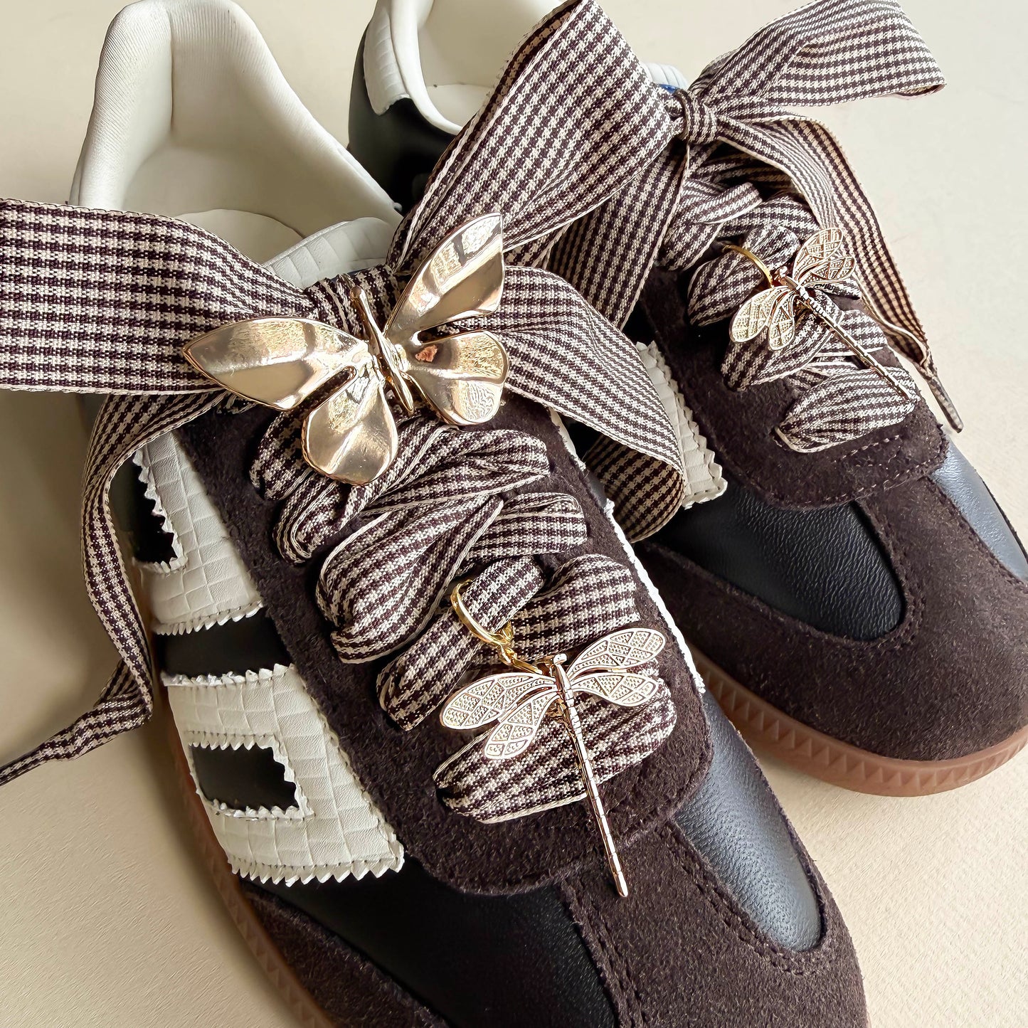 houndstooth laces with a gold butterfly and 2 golden dragonfly charms shoecased on a brown back 70 sneaker