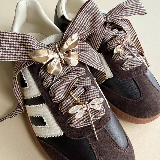 houndstooth laces with a gold butterfly and 2 golden dragonfly charms shoecased on a brown back 70 sneaker