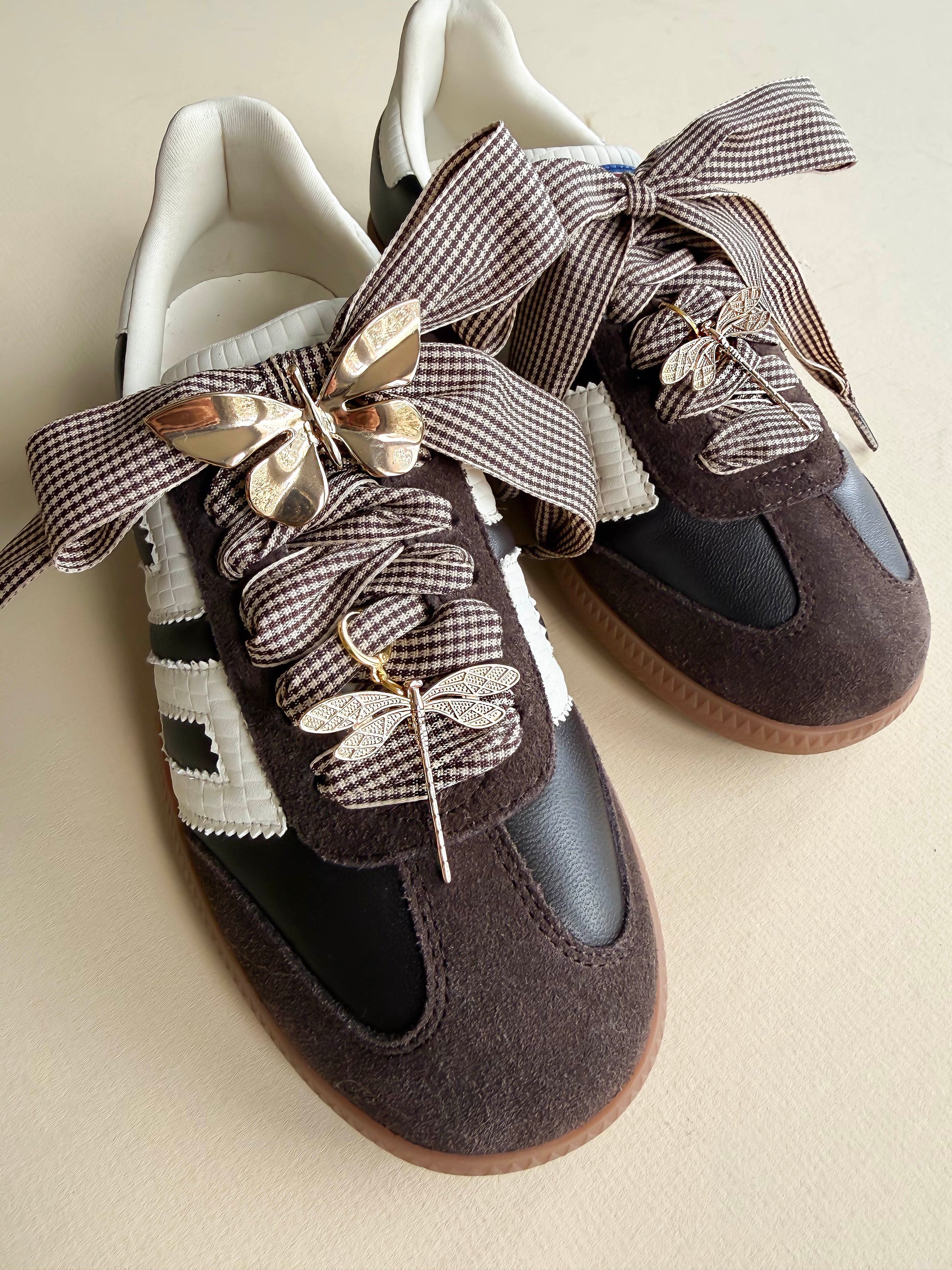 houndstooth laces with a gold butterfly and 2 golden dragonfly charms shoecased on a brown back 70 sneaker