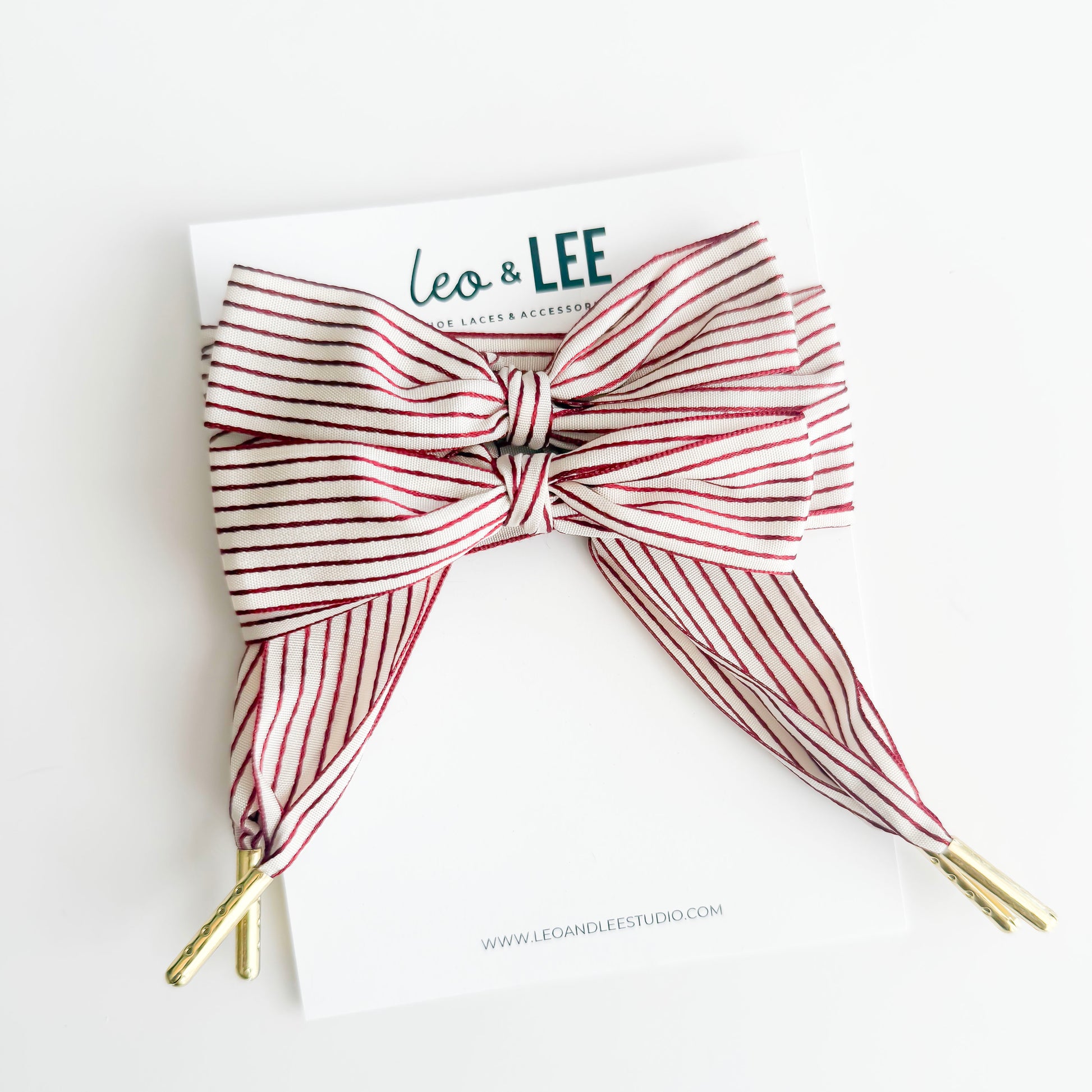 Red and white striped hair bow with gold tips on a white background, branded 'Leo & Lee'.