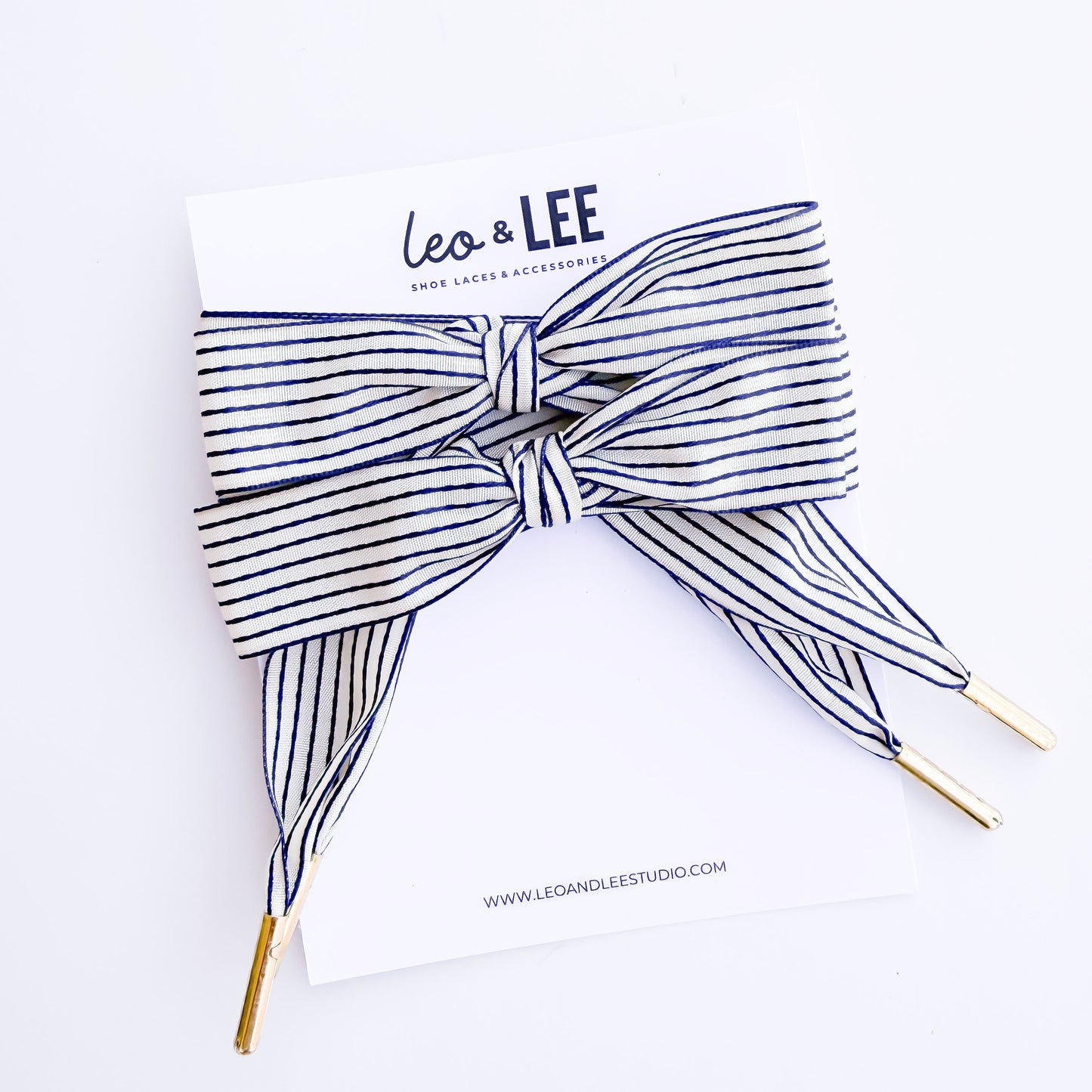 Striped bow headband with 'Leo & Lee' branding on a white background