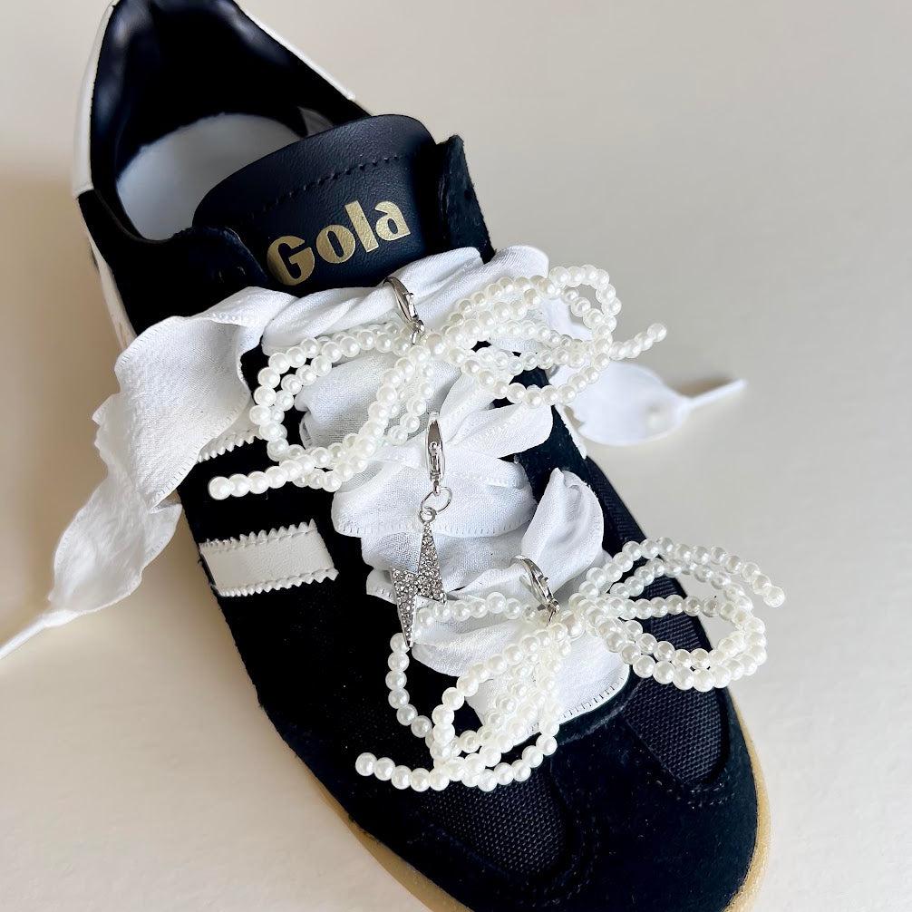 Leo + Lee white pearl and bow shoe charm set with elegant white ribbon laces, featuring a pearl chain and bow charm on a white background.