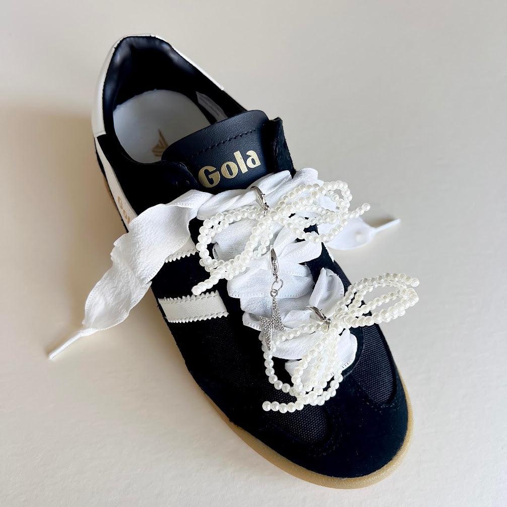 Leo + Lee white pearl and bow shoe charm set with elegant white ribbon laces, featuring a pearl chain and bow charm on a white background.