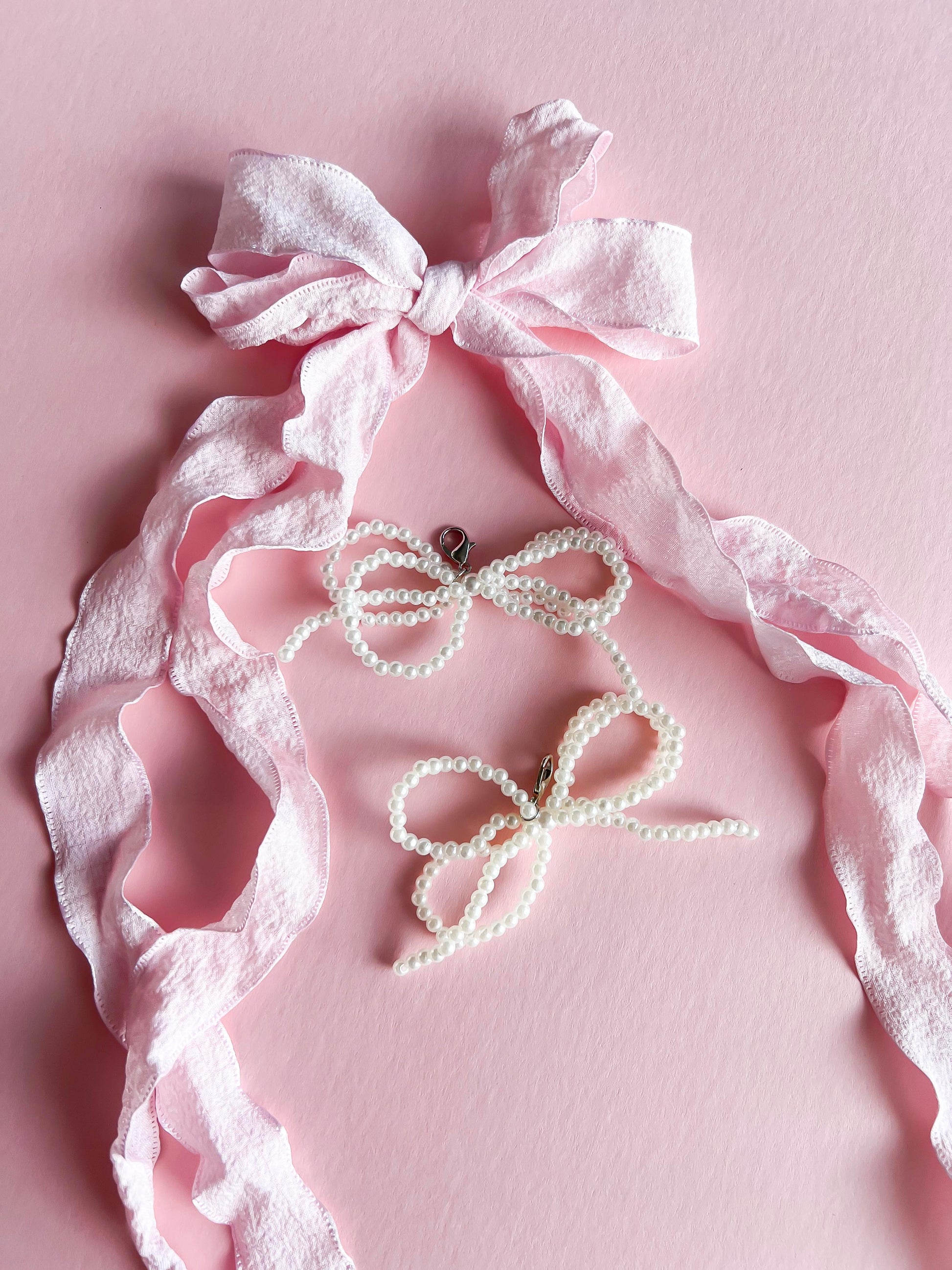 Pink ribbon lace and pearl bow shoe charms set, with a soft fabric ribbon and two pearl bow clips, displayed on a pink background