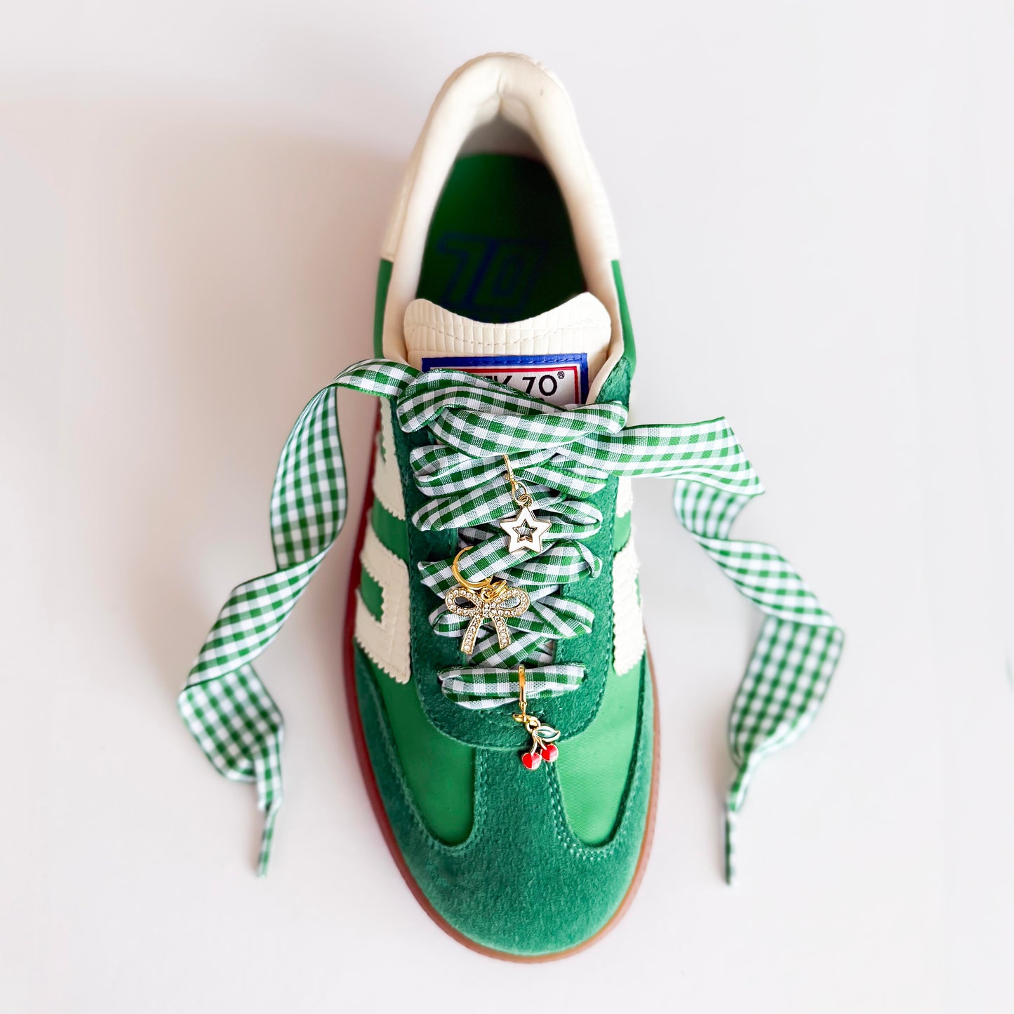 Green gingham bow shoelace accessories with gold sneaker charms – star, cherry, and rhinestone bow – laid out on a Leo and Lee Studio card.