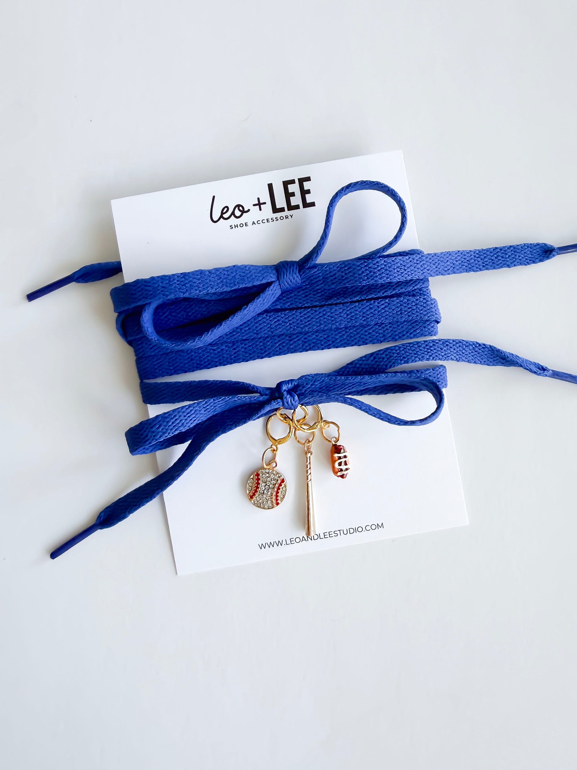 royal blue laces with sports-themed charms on a white card with 'Leo + Lee' branding.