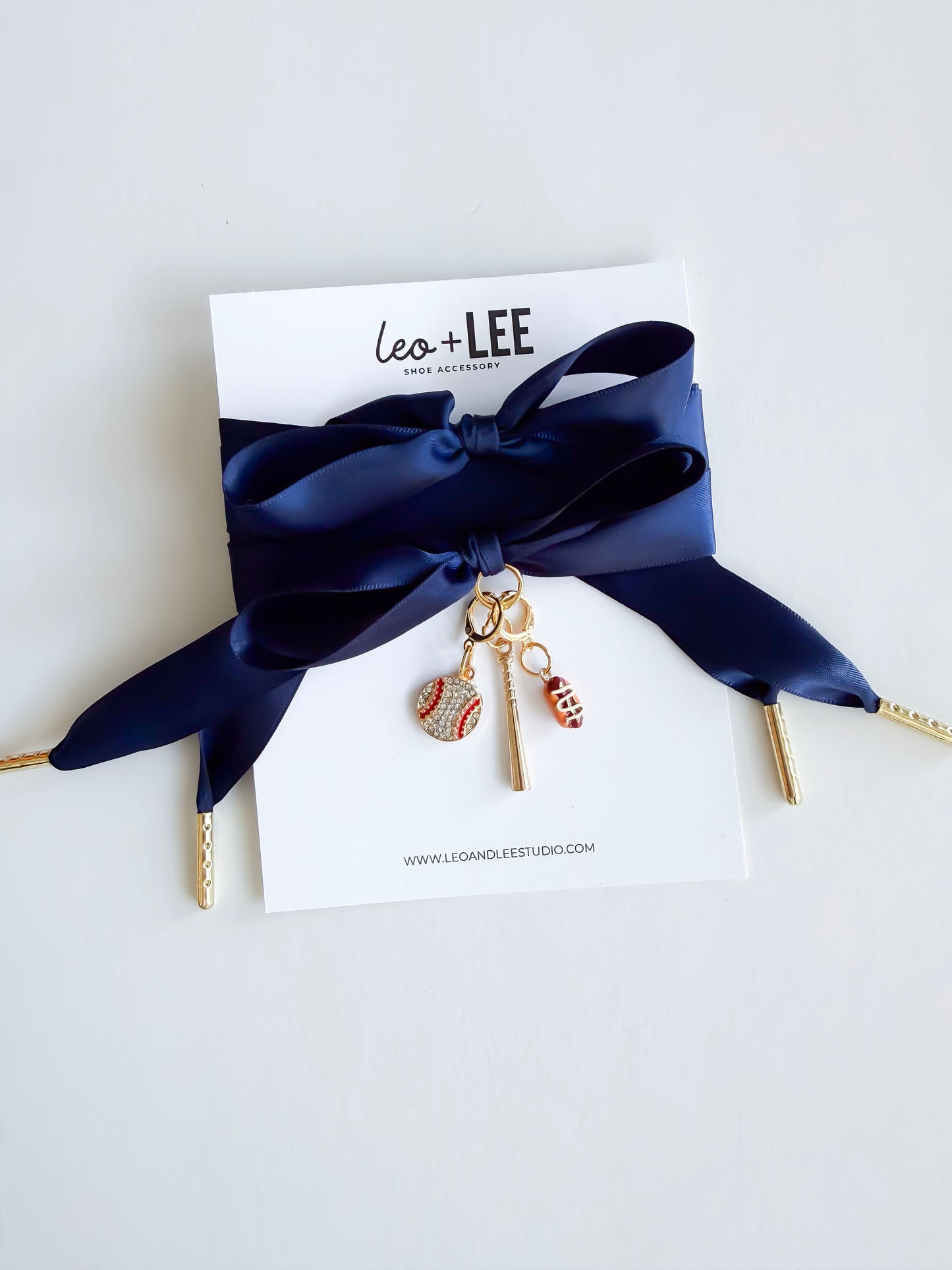 Navy Satin Laces with gold aglets with sports-themed  baseball charms on a white card with 'Leo + Lee' branding.